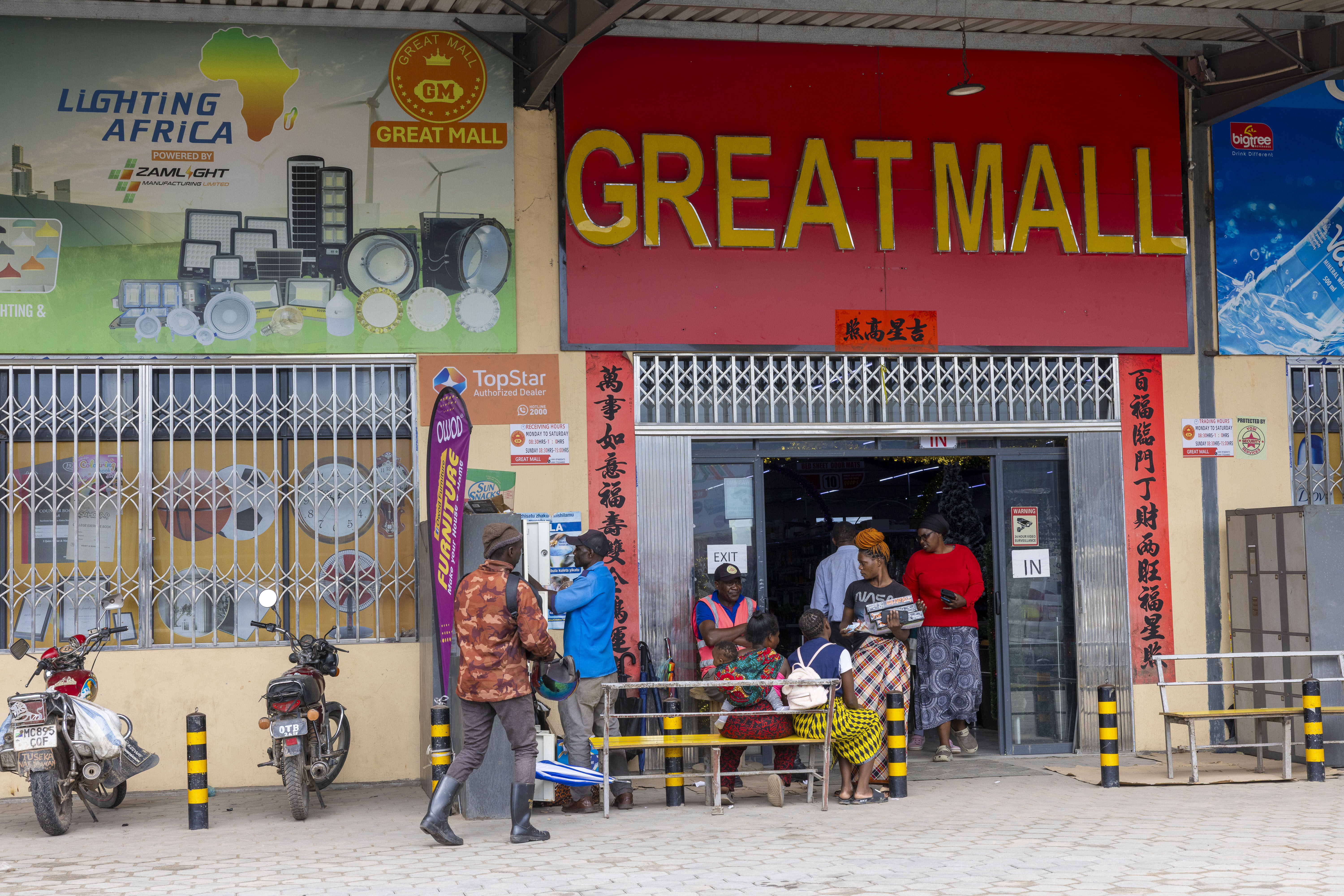 A street view of the "Great Mall" in Kapiri Mposhi, Zambia, with Chinese script on the facade and various individuals gathered outside.