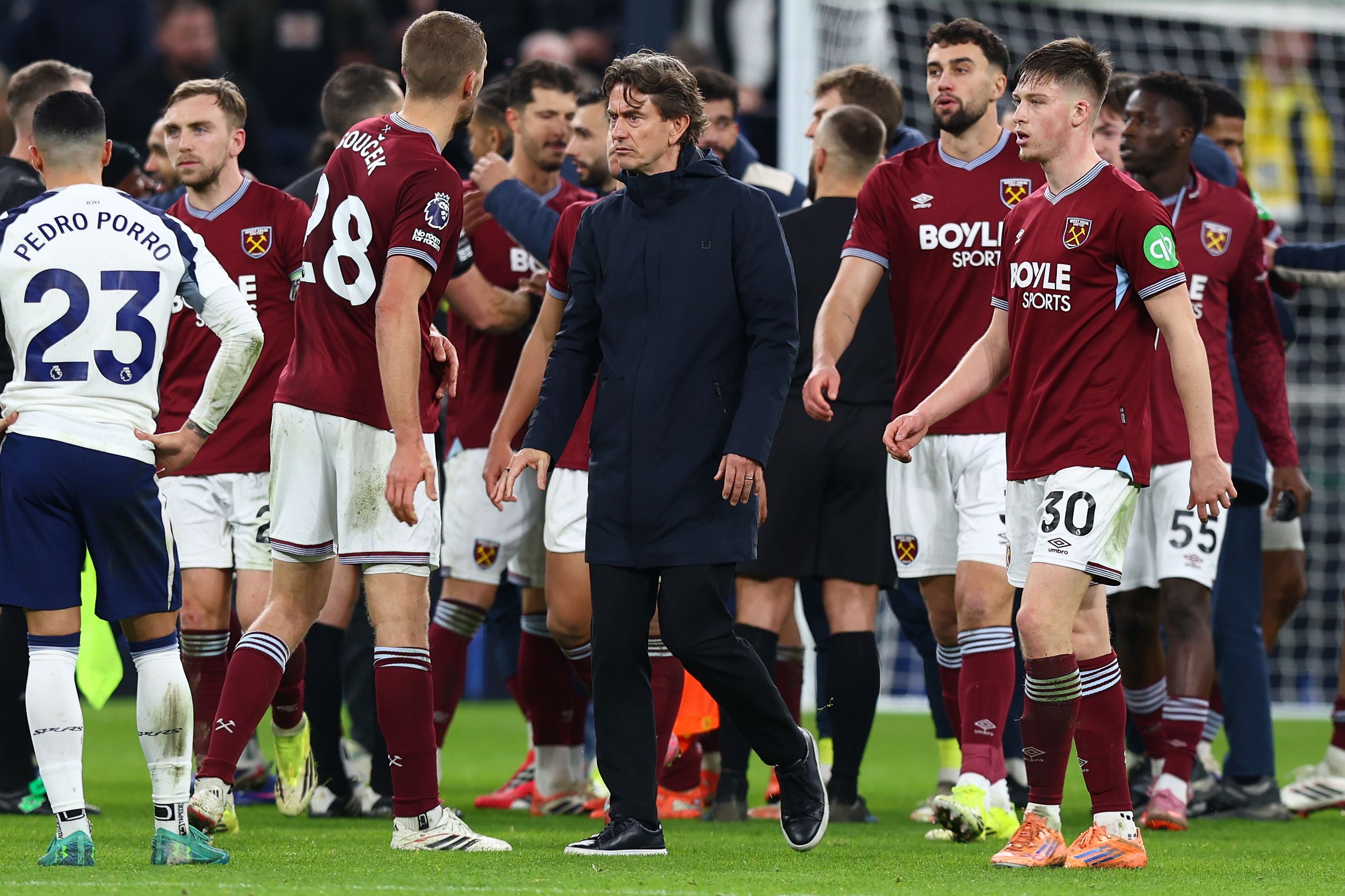 Tottenham Hotspur manager Thomas Frank walking on the field at full-time, surrounded by players from both teams.