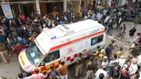 Sameer Khan An ambulance, surrounded by a huge group of people and police officials, in Madhya Pradesh's Indore city ferrying patients of a local diarhhoea outbreak caused by contaminated tap water