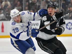 Tampa Bay Lightning right winger Pontus Holmberg and Los Angeles Kings' Andrei Kuzmenko chase down the puck during a game.