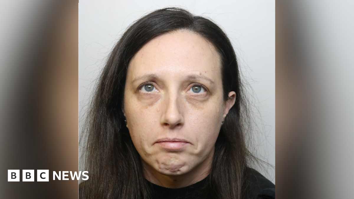 A police custody image of Heidi Bessant. She has shoulder length dark hair and wears a dark top. She is looking to the ceiling and frowning.