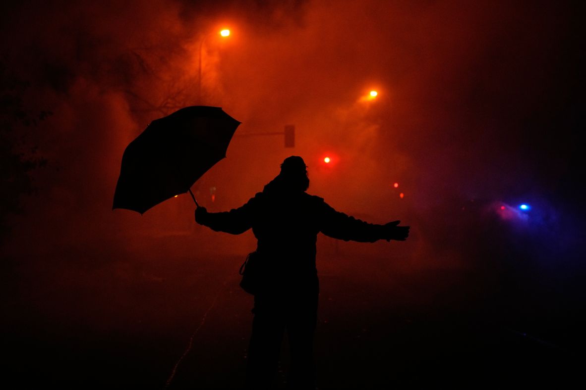 A protester holds an umbrella as they react to tear gas being fired by federal agents in Minneapolis on January 14.