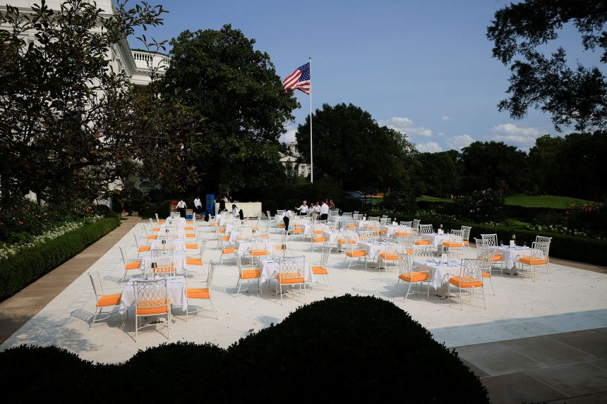 Waiters work on preparations for a dinner hosted by President Donald Trump on the newly renovated Rose Garden patio on September 5, 2025.