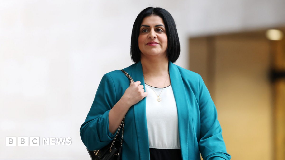 Home Secretary Shabana Mahmood arrives at the BBC in London. She is wearing a turquoise blazer and has a black handbag wrapped over her right shoulder