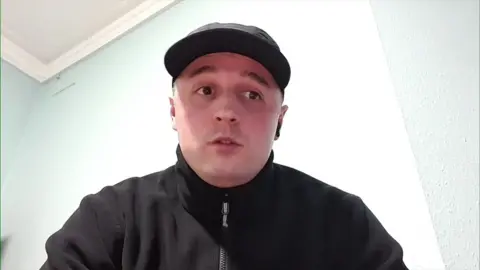 BBC Newsnight A man is seen wearing a black hat and a zipped-up black jacket.