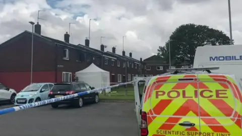 Image shows police and forensics vehicles outside the home of Sheila Jackson and Peter Greener in South John Street, St Helens, in the days after the blaze. 