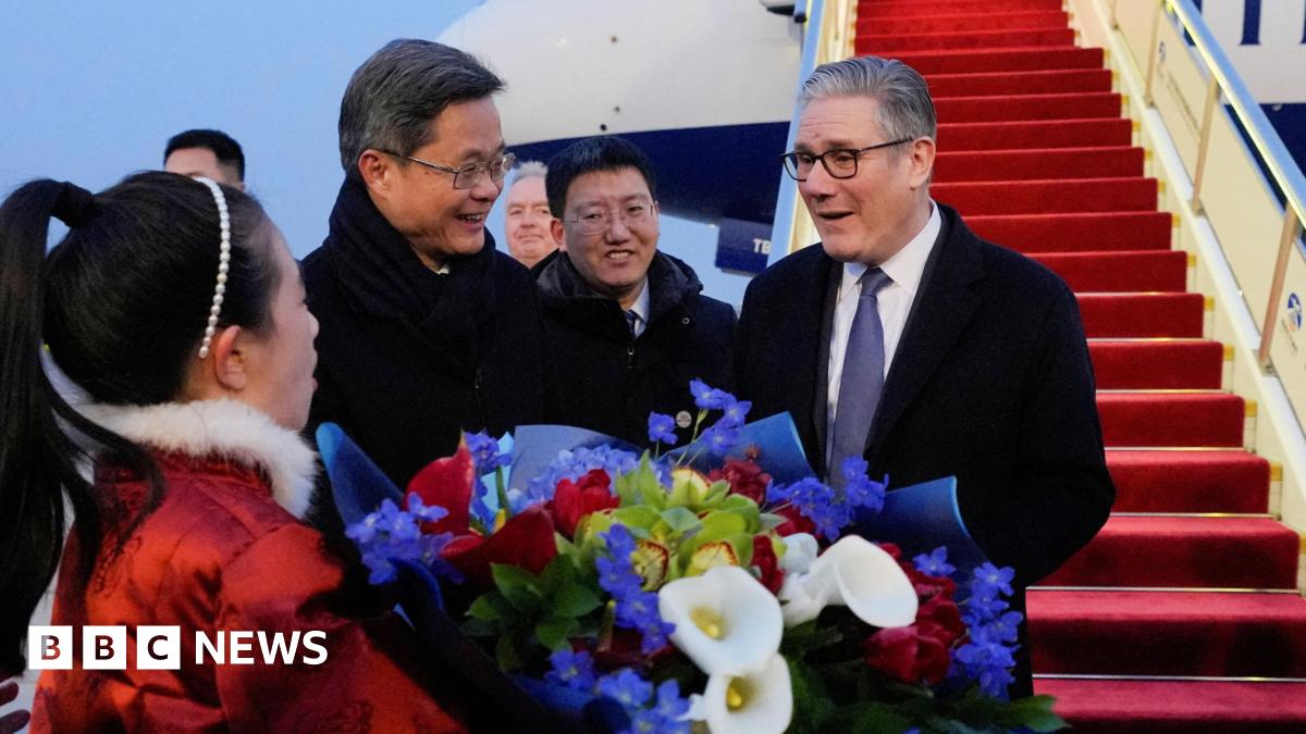 Keir Starmer reacts with delight as he receives a bouquet of flowers at an airport in Beijing from a woman in a red costume with a white fur collar. Chinese Finance Minister Lan Foan reacts with a smile