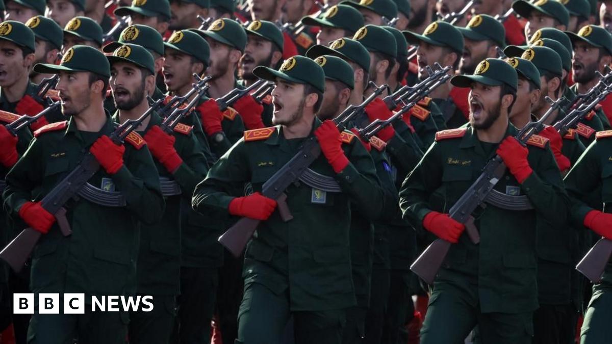 Iranian Revolutionary Guard Corps (IRGC) soldiers march in formation in September 2024. The group of men wear matching green and red uniforms and hold rifles