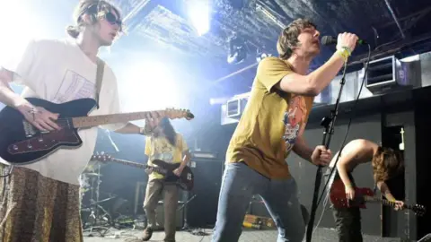 Getty Images All four members of Geese performing live on stage with their guitars