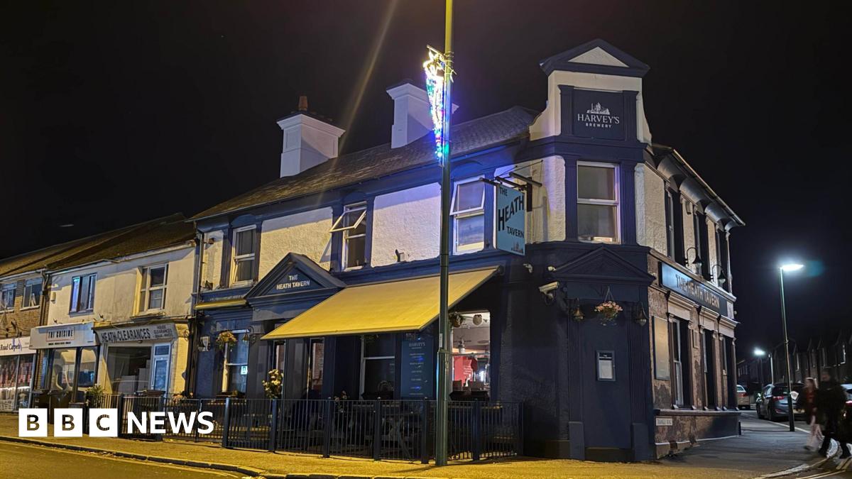 A pub building during the night. A Christmas light is switched on on a lamppost in front of the building.