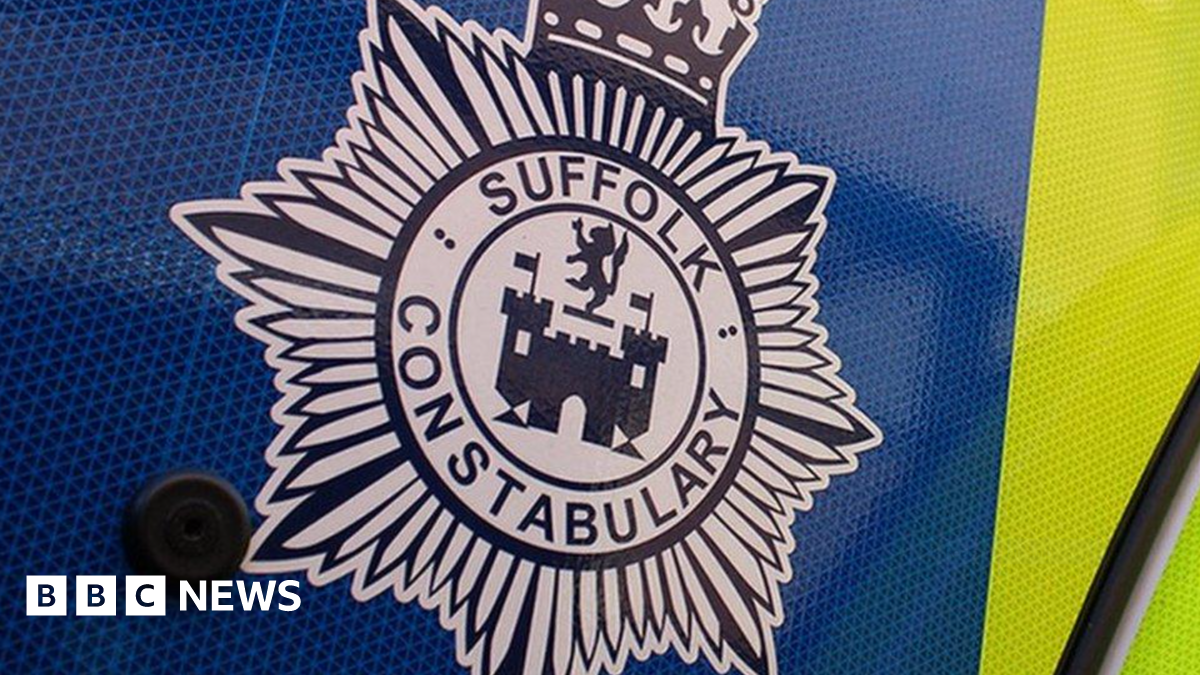 A close-up image of the Suffolk Police crest. It is black and white, and appears to be printed on a yellow and blue marked police car.