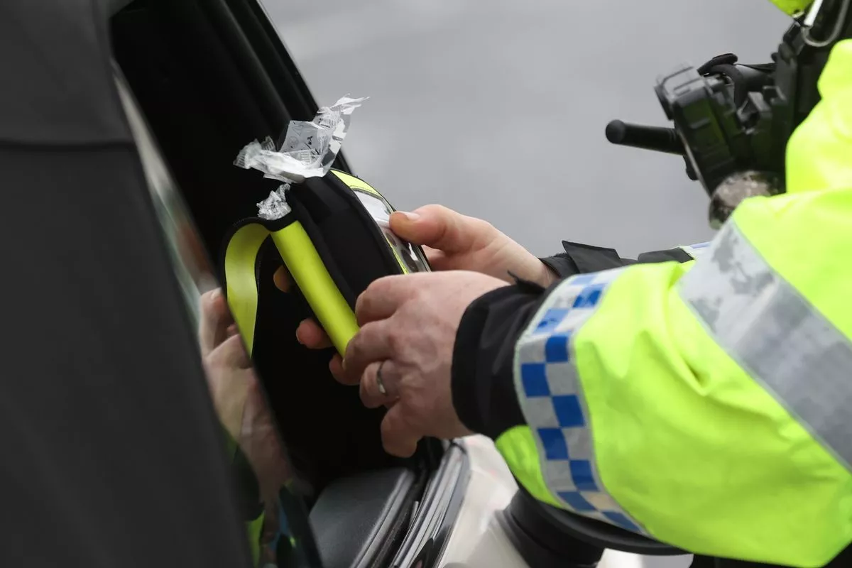 A police officer looking at a breathalyser 