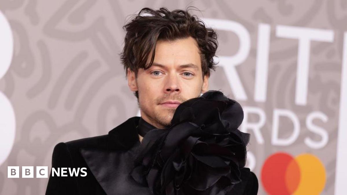Harry Styles in a black designer jacket with over-sized flower detail at his neck, at the Brit Awards