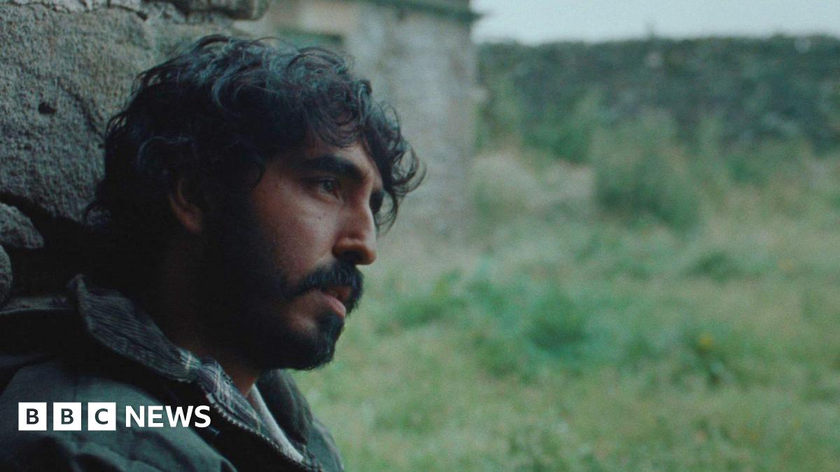 A man sat against a wall staring ahead