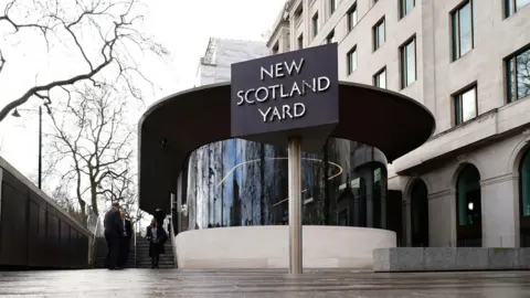 PA Media Photo of Met Police headquarters with a rotating sign on a pole outside that says New Scotland Yard.