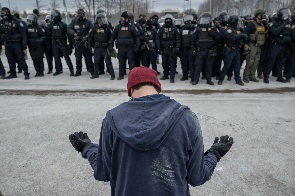 A demonstrator stands in front of law enforcement officers outside the Bishop Henry Whipple Federal Building on January 15.