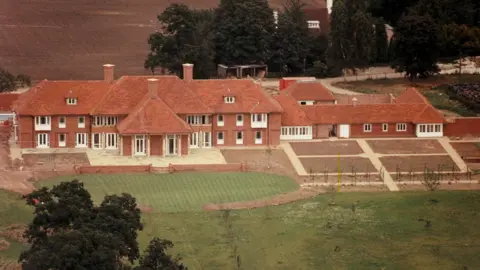 Shutterstock An aerial view of Sunninghill Park, showing a large two-storey red-brick mansion with dormer windows and a long wing extending on the right-hand-side of the image. 