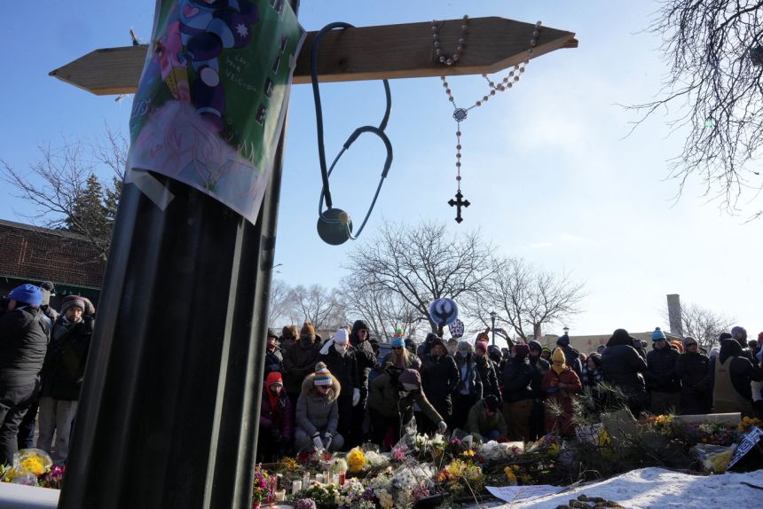 A cross and a stethoscope hang at a makeshift memorial as people gather at the site where a man identified as Alex Pretti was fatally shot by federal immigration agents trying to detain him, in Minneapolis on January 25. 