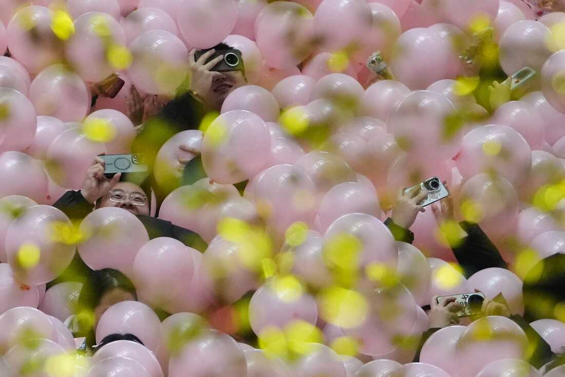 Reveler use their smartphones to film the falling balloons and confetti  