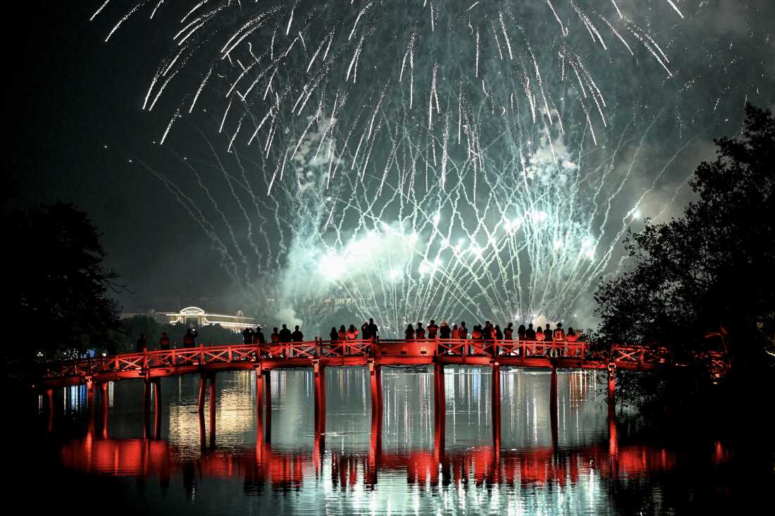 Revellers watch the New Year's Eve fireworks from the The Huc Bridge at Hoan Kiem Lake in Hanoi 