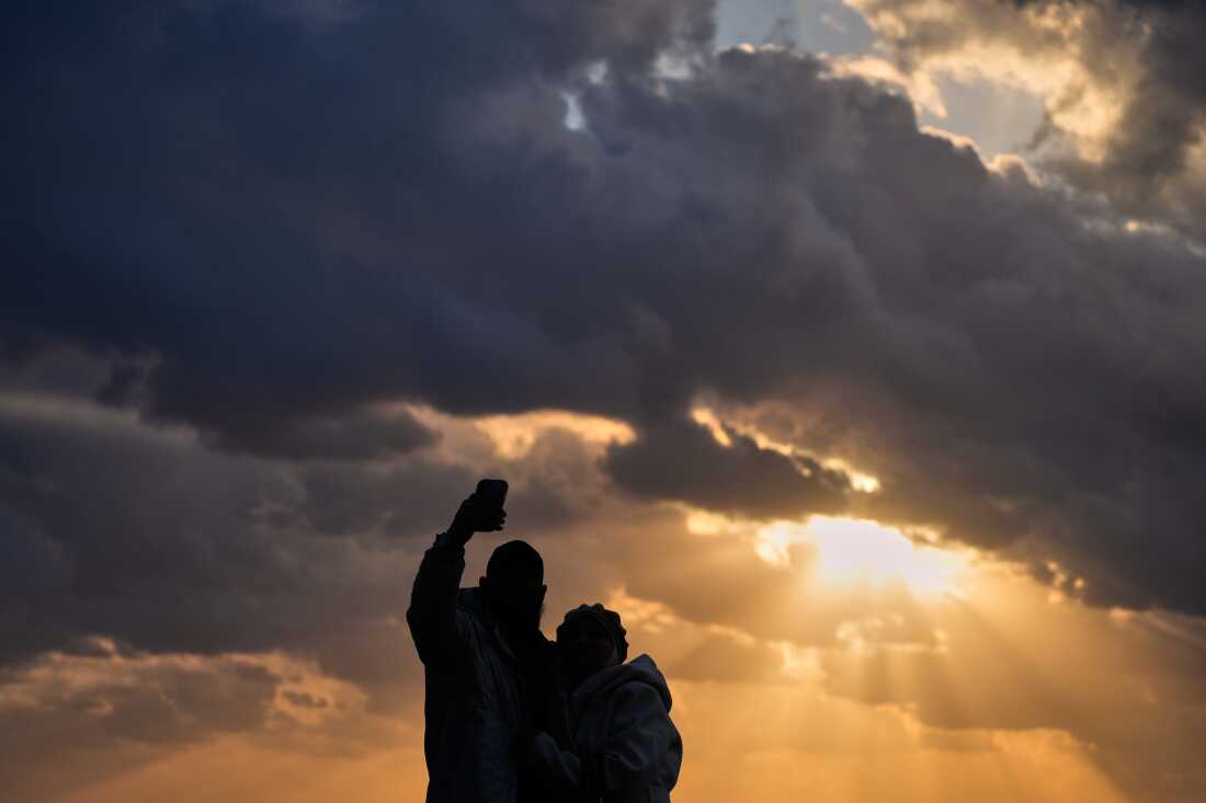 A couple takes a selfie as the last sunset of 2025 is seen over the Mediterranean Sea in Beirut, Lebanon