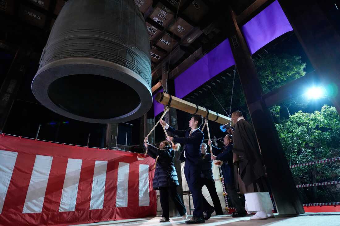 People strike a giant bell to celebrate the New Year at the Zojoji Buddhist temple, minutes after midnight Thursday Jan. 1, 2026, in Tokyo. 