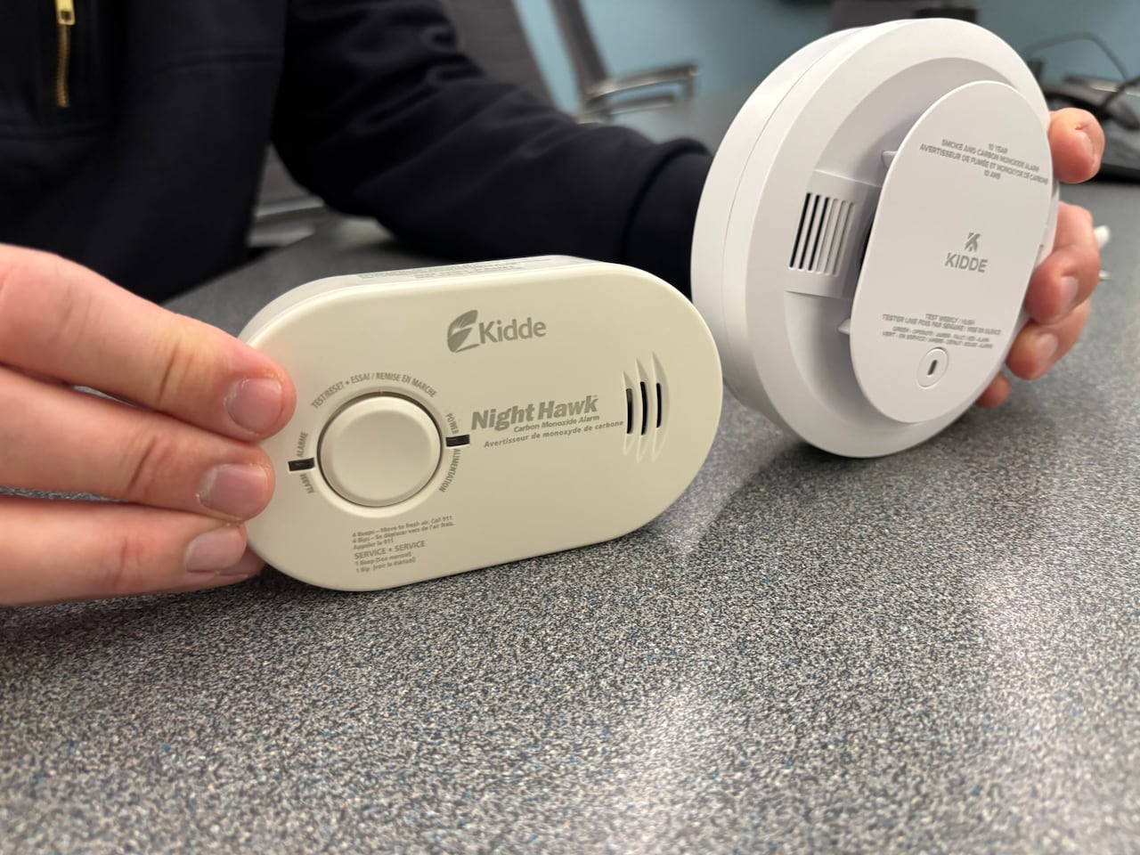 Two examples of common carbon monoxide alarms. The alarm on the left is a plug-in model; the one on the right is a ceiling-mounted unit.