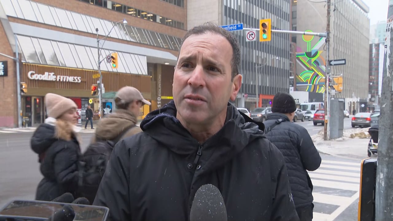 a man in a black jacket stands in front of a intersection