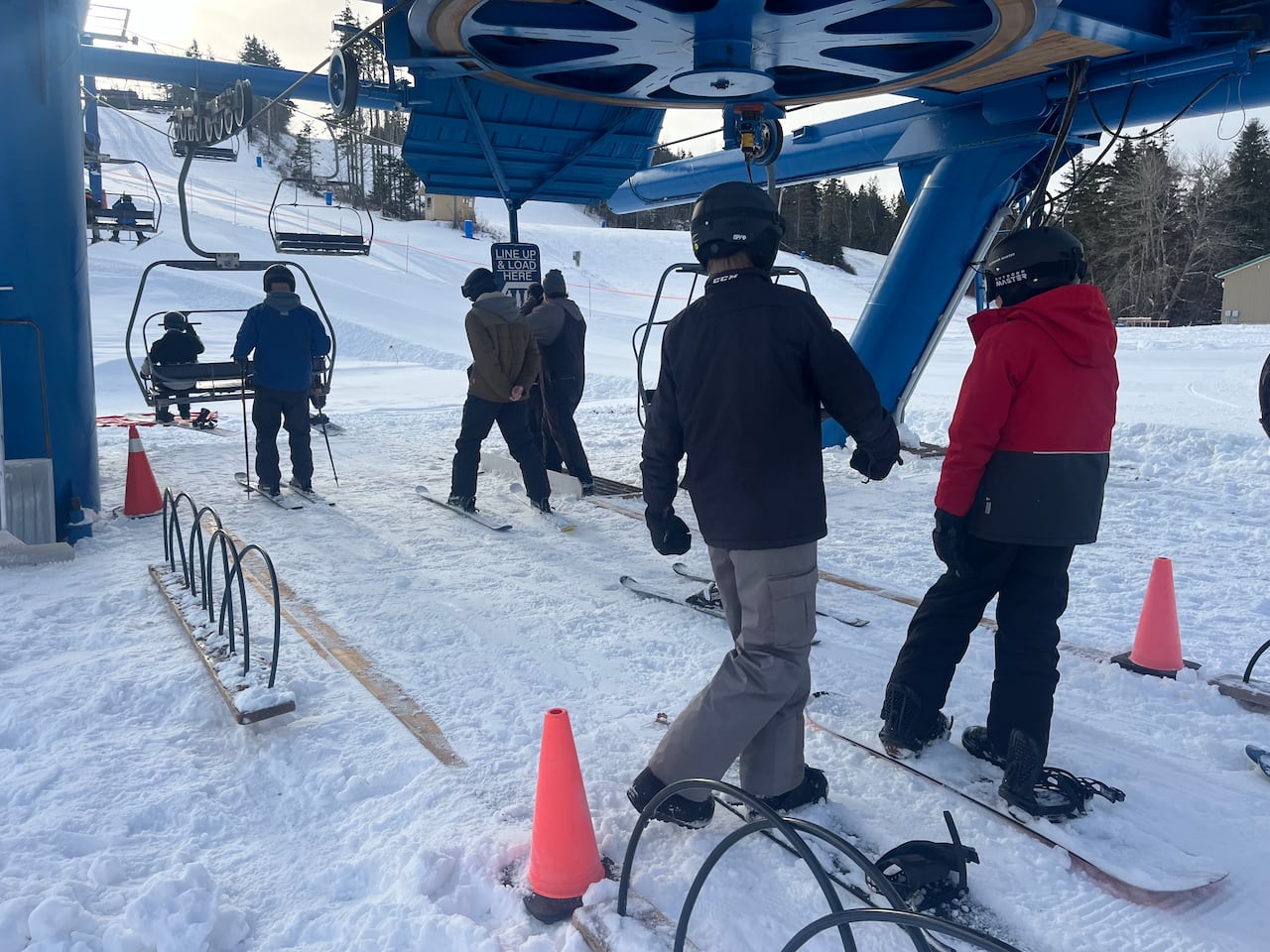 People at a ski lift at the bottom of a hill 
