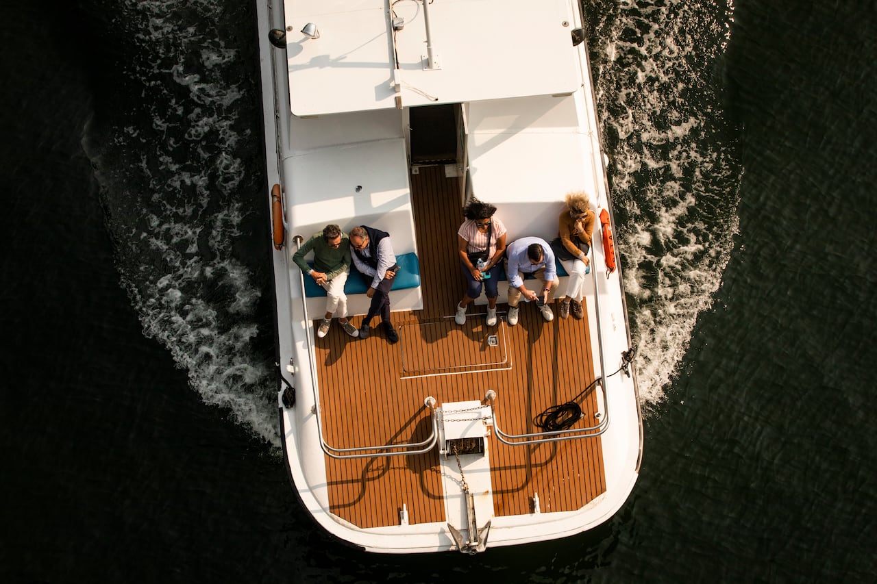 Boaters sit on the front of a large yacht as it moves across water.