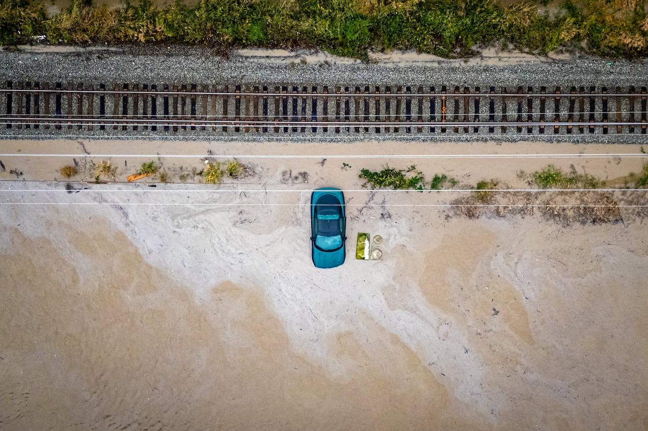 The top of a green car is visible as it is surrounded by brownish water.