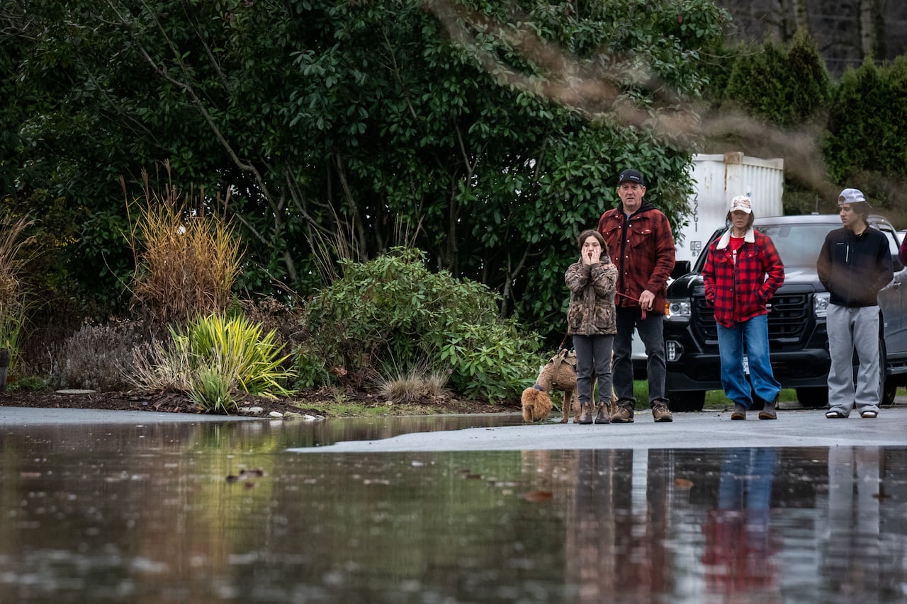 A young girl stands with her hands on her face as she watches flood water rise on a street.