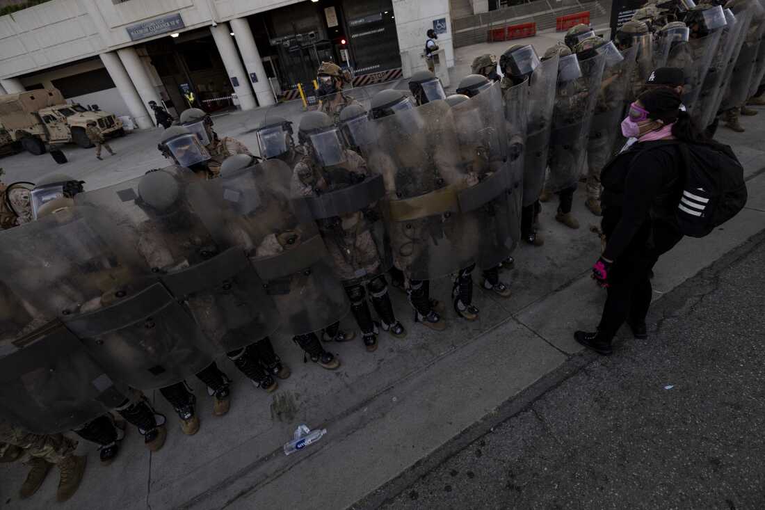 U.S. Marines and National Guard troops patrol the entrance of the Metropolitan Detention Center in Los Angeles as demonstrators gather on July 4, 2025.