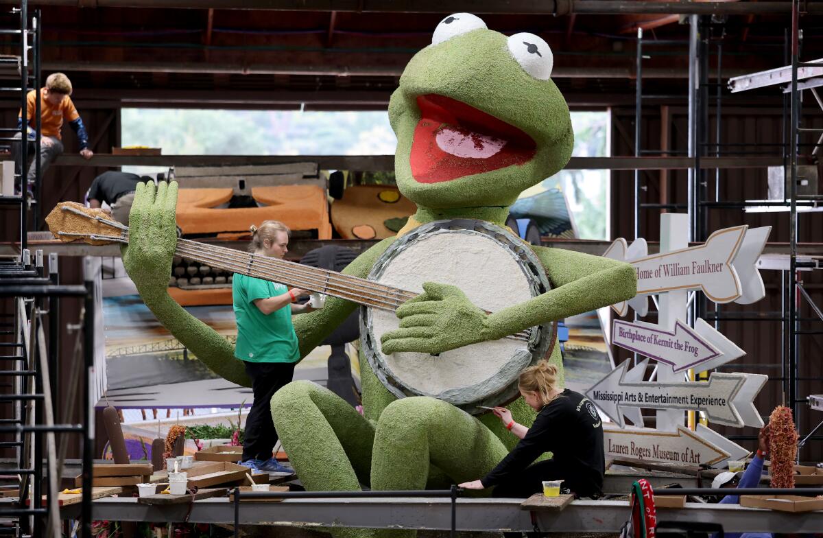 Volunteers decorate a Kermit the Frog parade float