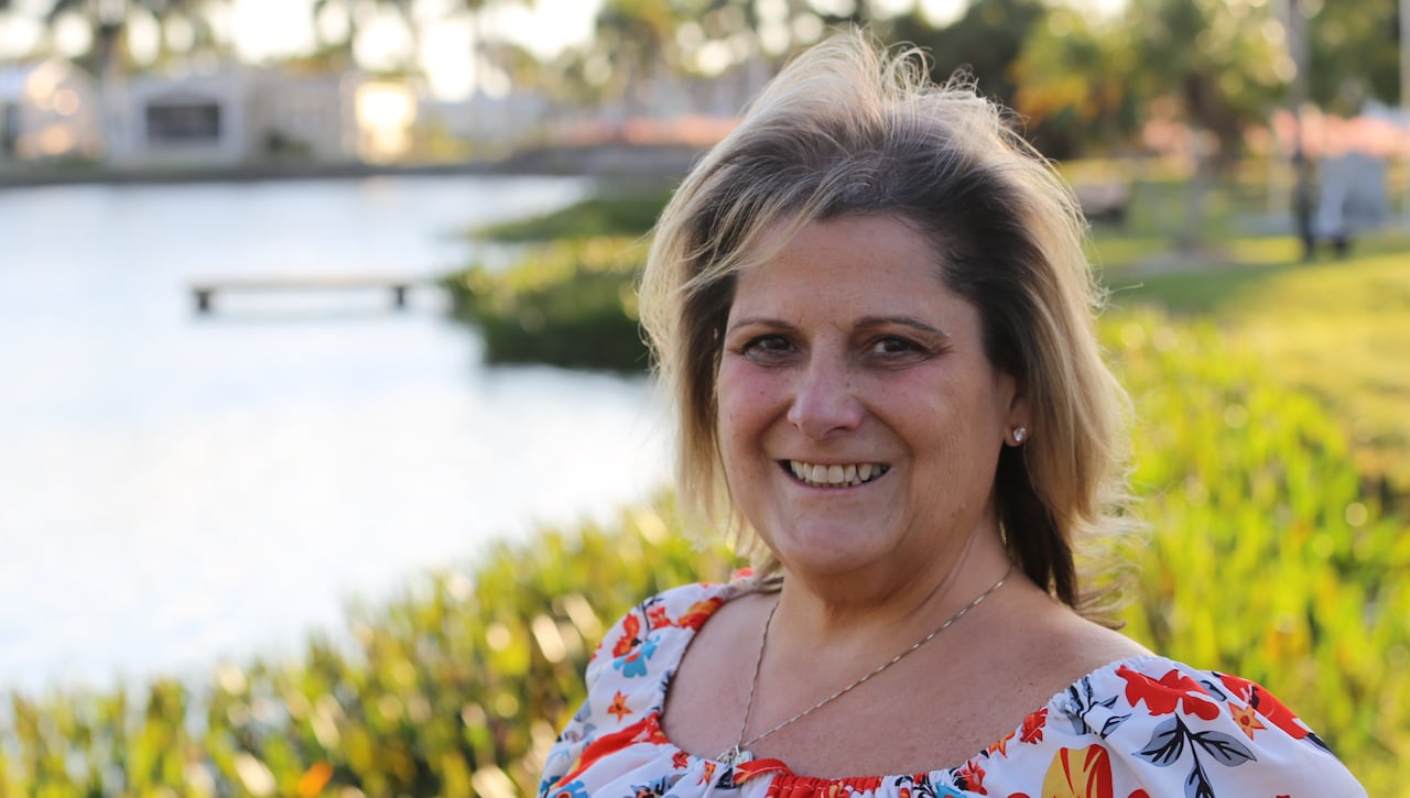 A woman wearing a dress stands beside a body of water.