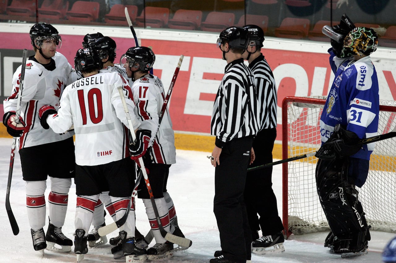 Five hockey players and two referees standing on the ice next to the net