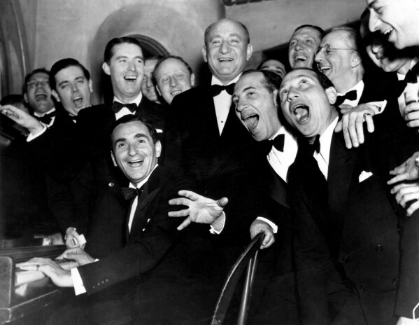 Irving Berlin, at the piano, and friends celebrate his 25th year since he wrote "Alexander's Rag Time Band" at a banquet in his honor in Hollywood, Ca., Jan. 20, 1936. Standing behind Berlin, at right, is Joseph Schenck, film producer. In front row singing together are two of the Marx Brothers, Chico and Harpo. (AP Photo, File)