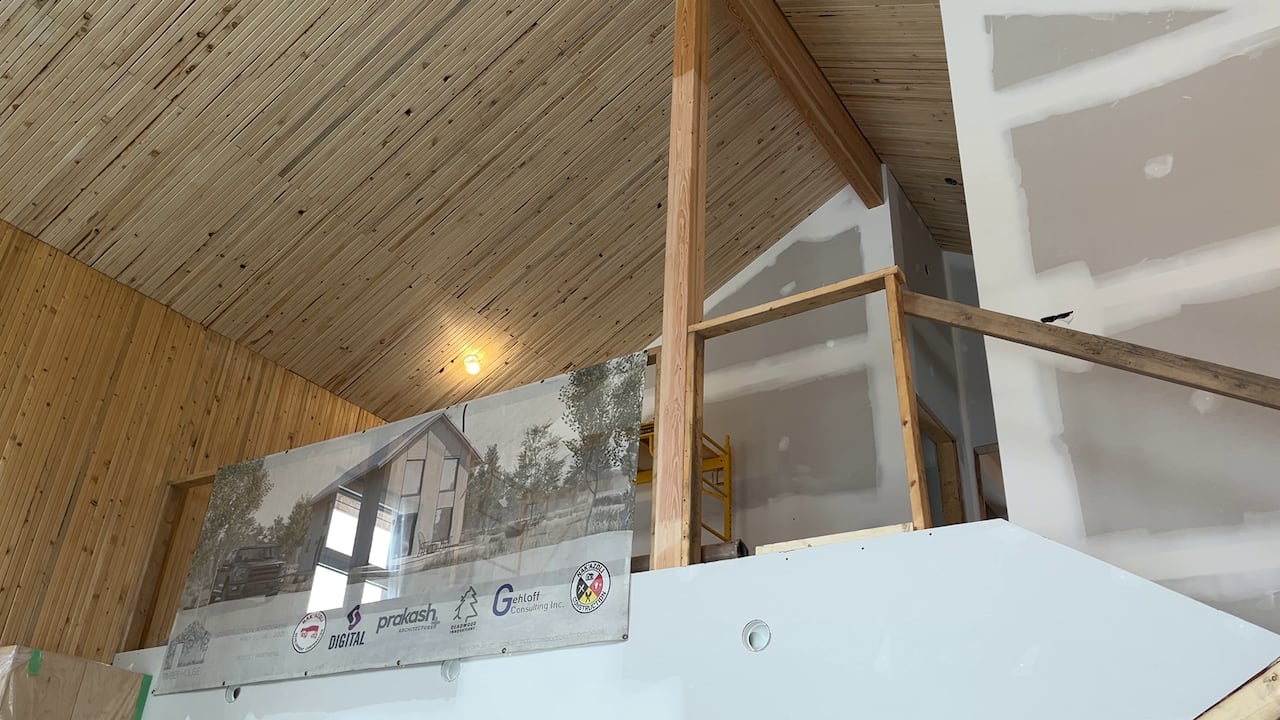 Vaulted timber ceilings pictured inside of a home with unfinished drywall. 