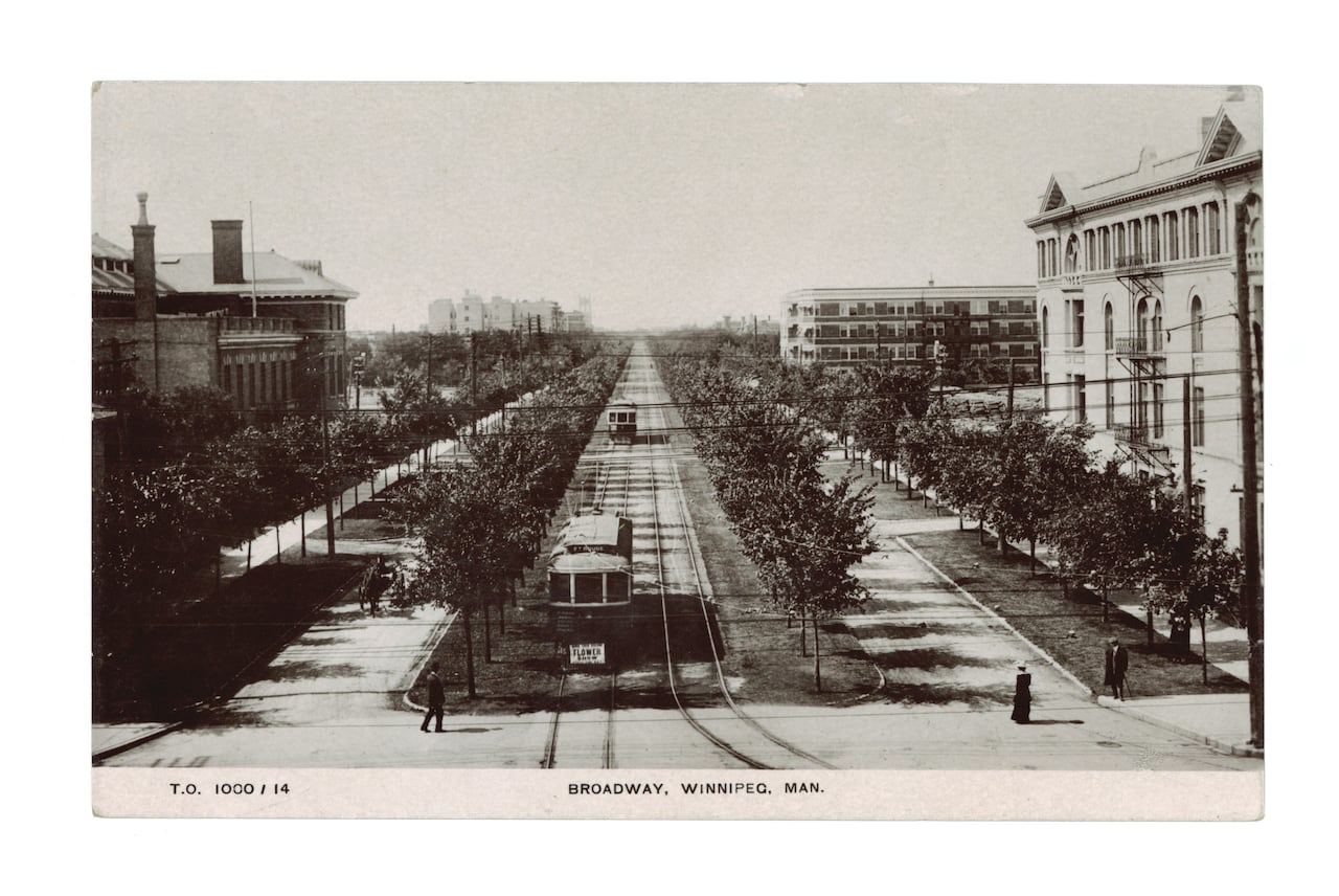 Black and white image of a long, tree-lined boulevard with a streetcar