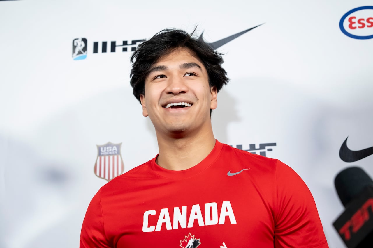 A male ice hockey player smiles while addressing the media.