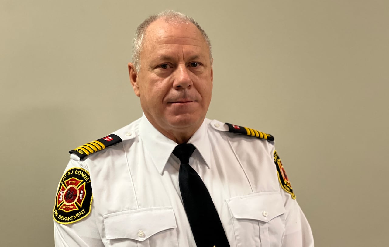 A man with grey and balding hair wearing a firefighter's uniform style shirt 
