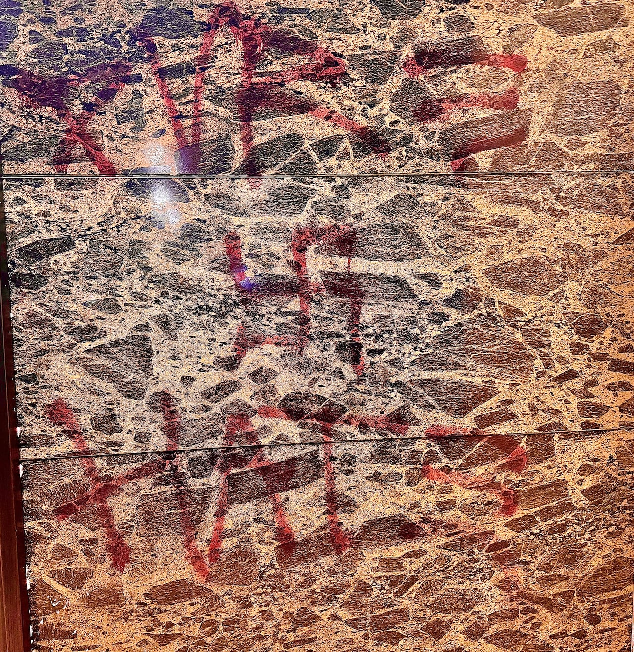 Red paint was sprayed in a brown wall.