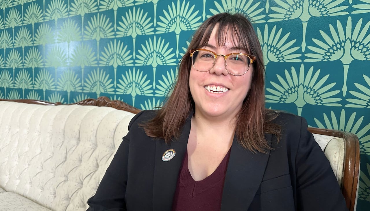 A woman sits in front of a beautifully painted wall.