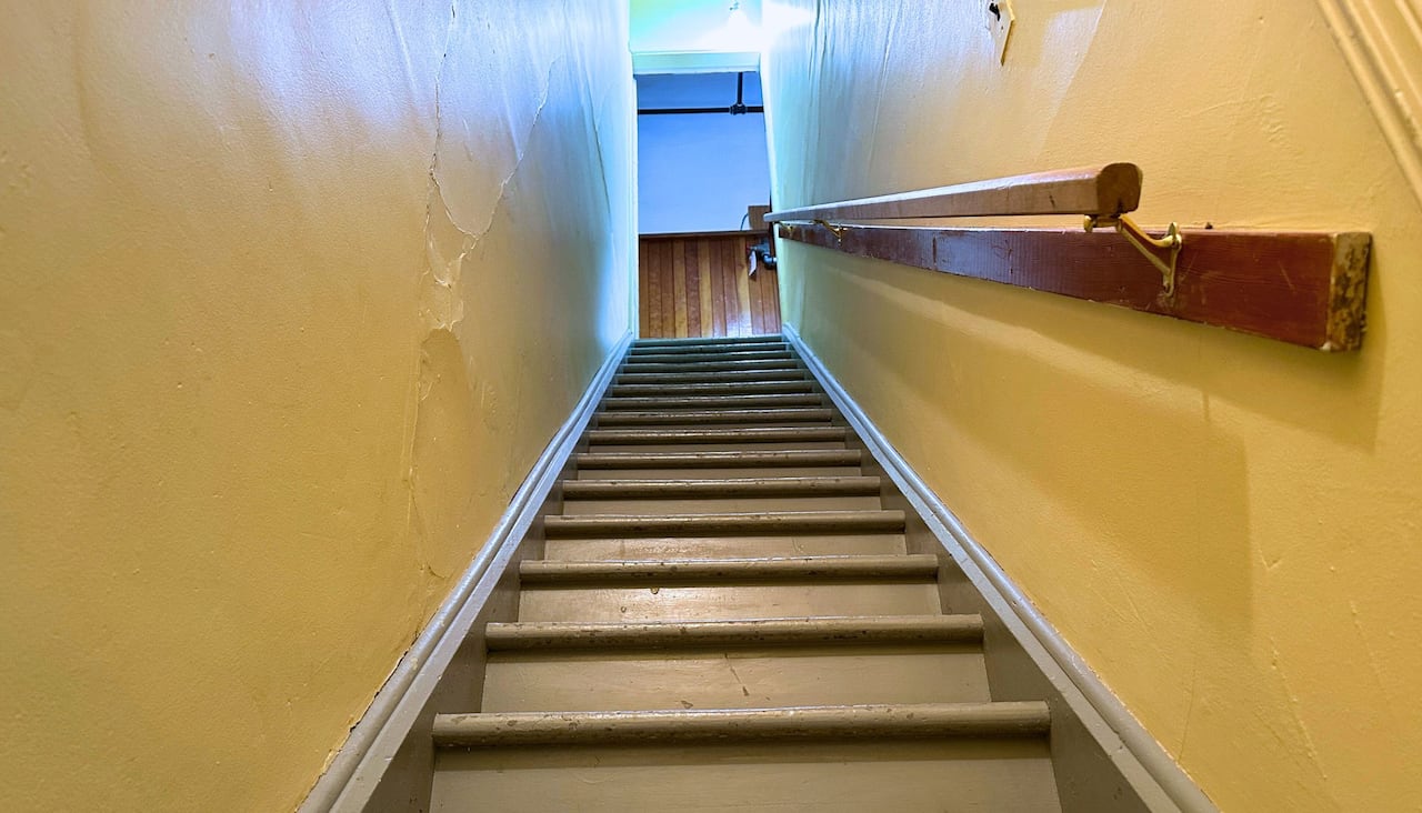 A narrow stairwell with paint peeling. 