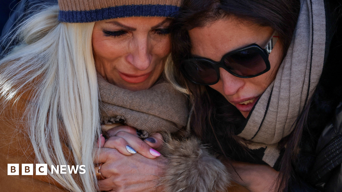 A young man in a black puffer coat takes a plant to the shrine