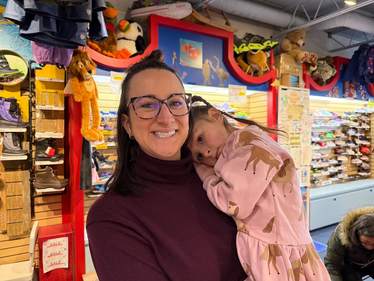 a woman in a burgundy long sleeve holds a baby in a pink jumper