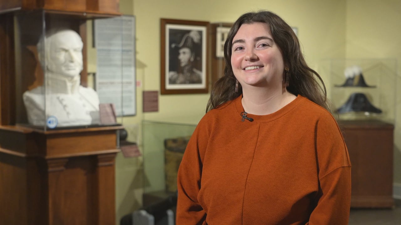 Woman stands in the Bytown Museum surrounded by historic artifacts.