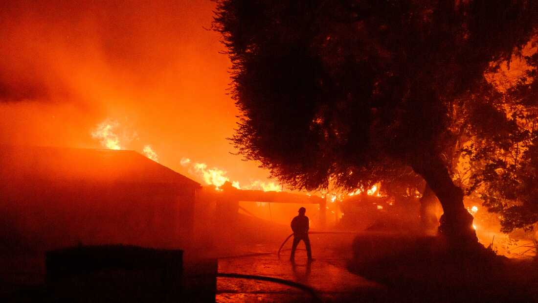 A firefighter works as homes burn during the Eaton fire in the Altadena area of Los Angeles County, Calif., on Jan. 7, 2025. 