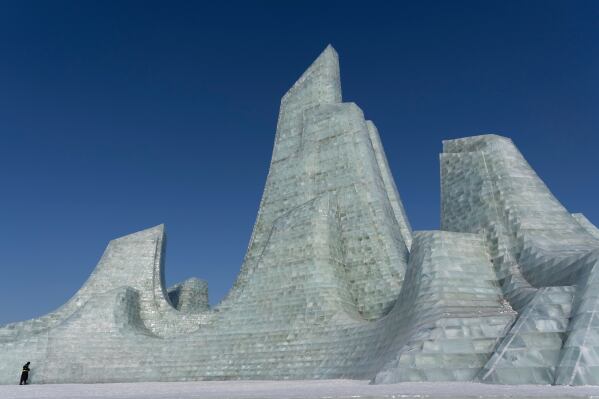A security guard is dwarfed by a huge ice structure at the annual Ice and Snow Festival in Harbin in northeastern China's Heilongjiang province on Sunday, Jan. 4, 2026. (AP Photo/Ng Han Guan)