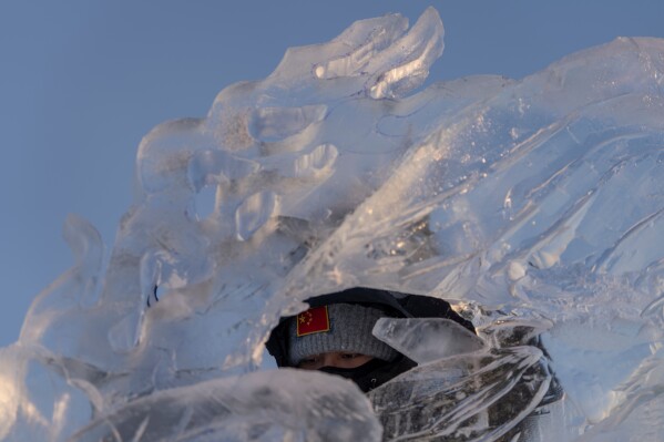 An ice sculptor looks through his work as he prepares for competition in the annual Ice and Snow Festival held in Harbin in China's Heilongjiang province on Saturday, Jan. 3, 2026. (AP Photo/Ng Han Guan)